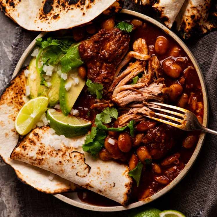 Mexican Chipotle Pork and Beans with tortillas, avocado and limes on the side